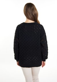 Maglione nero lavorato a maglia con un motivo a trama larga, collo rotondo e maniche ampie. Orlo e polsini a coste con un design testurizzato sulle maniche.