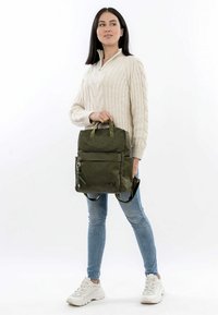 Olivgrön texturerad ryggsäck med dubbla handtag ovanpå, justerbara axelremmar, framficka med dragkedja och en minimalistisk design.