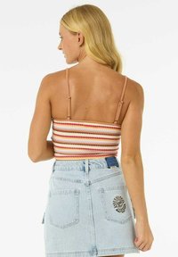 Top court rayé avec des bretelles ajustables en rouge, orange et crème. Assorti à une jupe en denim bleu clair avec des broderies sur les poches arrière.