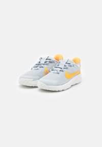 Chaussures de sport grises avec des accents orange, dotées d'un dessus texturé, de lacets et de semelles en caoutchouc blanc. Design à bout rond et col rembourré.