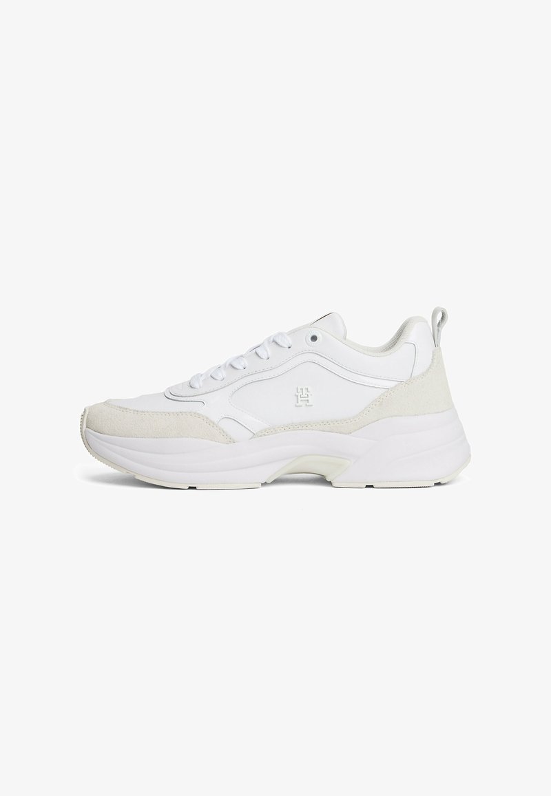 Białe sneakersy wykonane z materiałów skórzanych i zamszowych, z masywną podeszwą, okrągłym noskiem, sznurowanym przodem oraz teksturowymi akcentami po bokach.