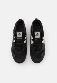 Černé sportovní boty s síťovaným a syntetickým svrškem, s bílými pruhy, černými tkaničkami a texturovanou podrážkou. Mezi doplňky se nachází branding „RAIN.RDY“. 