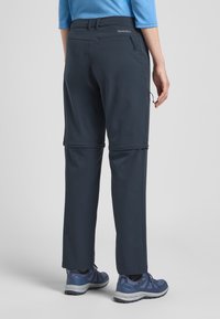 Marine hikingbroeken met ritszakken, elastische tailleband en verstelbare boorden. Gecombineerd met grijze wandelschoenen. Glad, duurzaam materiaal.
