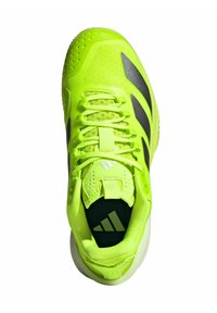 Scarpa atletica gialla neon con upper in tessuto testurizzato, accenti neri e colletto imbottito. Presenta un design con lacci e suola in gomma.