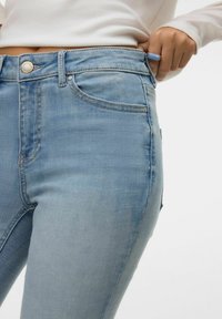 Šviesiai mėlynos džinsinės kelnės su siauru kirpimu, penkių kišenių dizainu ir klasikinėmis siūlėmis. Audinys šiek tiek tempiasi, kad būtų patogiau dėvėti.