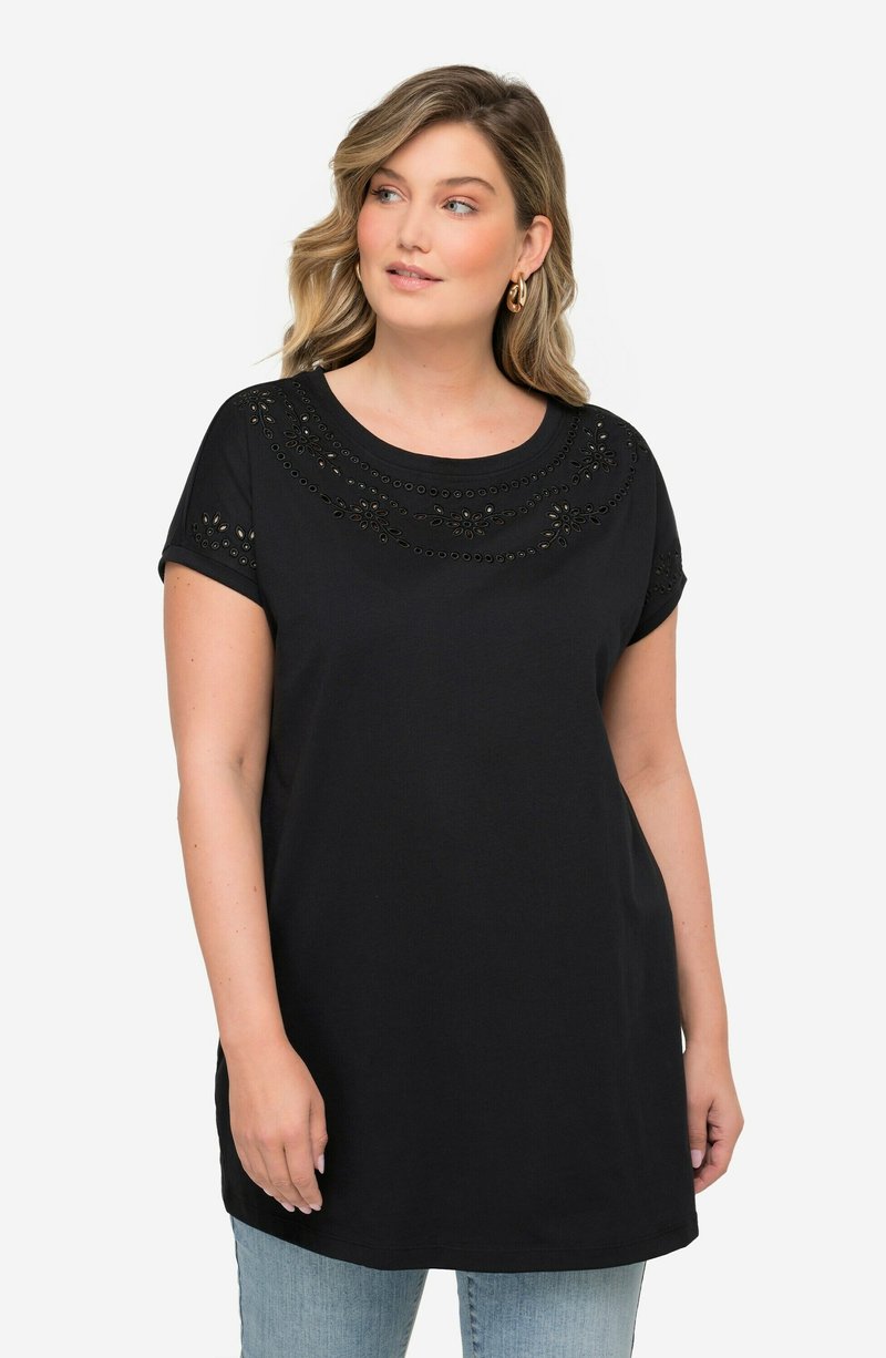 Camiseta negra de manga corta, cuello redondo y patrones decorativos recortados a lo largo del escote y las mangas. Corte casual, textura suave.