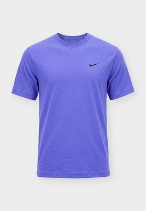 Fialové krátké sportovní tričko Nike s kulatým výstřihem a černým logem Swoosh na levé straně hrudi, zobrazené na bílém pozadí.