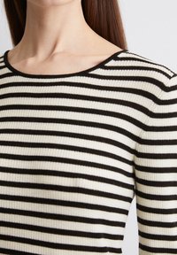 Gestreifter Strickoberteil in Schwarz und Weiß mit gerippter Struktur, breitem, rundem Ausschnitt und drei Viertellängenärmeln.