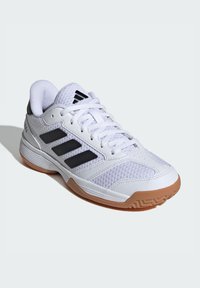 Chaussure de sport blanche avec un upper en mesh respirant, trois rayures noires et une semelle en caoutchouc naturel avec un motif de traction texturé.