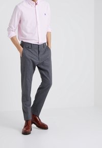 Camicia button-up a righe rosa chiaro, pantaloni grigi su misura e stivali stringati marroni. Tessuto liscio con design slim fit e colletto classico.
