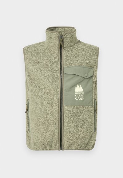 Fleeceový vest v tlmenej zelenej farbe s plným zipsom a vysokým golierom. Obsahuje predné vrecko so záklopkou na gombík a logom a bočné zipsové vrecká.
