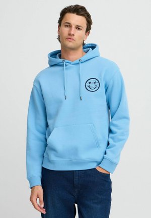 Felpa leggera azzurra realizzata in tessuto morbido, dotata di tasca frontale e un logo circolare nero sul lato sinistro del petto. Cappuccio con cordino regolabile.