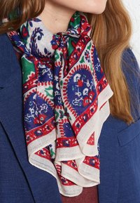 Bufanda de varios colores con diseños en rojo, azul y verde, hecha de tela ligera, que se lleva drapeada alrededor del cuello.
