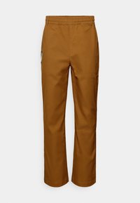 Pantalon beige à jambes droites avec ceinture élastique et poche latérale ornée d'un patch brodé. Tissu lisse et léger.
