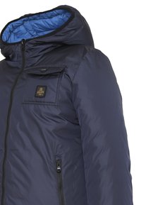 Giacca imbottita blu navy con cappuccio, caratterizzata da un materiale esterno liscio, chiusura zip frontale e tasca sul petto con un patch del logo.