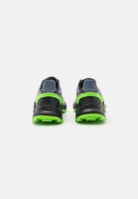 Chaussures de sport pour hommes avec une tige grise texturée, des accents noirs et une semelle en caoutchouc verte. Elles présentent un talon rembourré pour un soutien optimal.