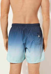 Plavky s gradientním designem přecházejícím z námořnické modré do světle modré, s elastickým pasem a zadní kapsou.