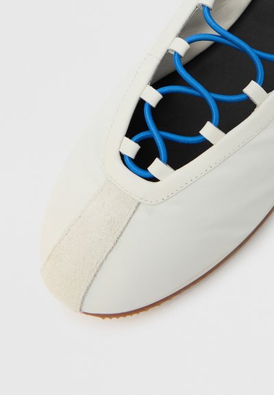 Λευκό παπούτσι με λείο δέρμα στο επάνω μέρος, μαλακή λε�πτομέρεια σουέτ και μπλε διακοσμητικά κορδόνια. Στρογγυλή μύτη και εύκαμπτη εξωτερική σόλα από καουτσούκ.