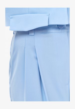 Lichtblauwe, op maat gemaakte broek met plooi-detail en bijpassend cropped jack, dichtgeknoopt bij de taille.