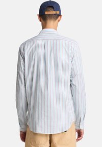Gestreepte langelm-Shirt in lichte kleuren. Heeft verticale strepen in pastel tinten, een puntige kraag en een merklabel op de kap.