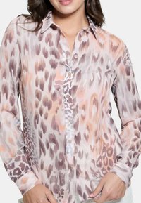 Blusa a maniche lunghe in tessuto leggero e stampato con tonalità di rosa, grigio e crema in un design a stampa leopardata; chiusura frontale con bottoni.