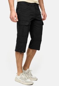 Shorts cargo noirs avec plusieurs poches et un ourlet à cordon de serrage. Fabriqués en tissu robuste, présentant une coupe décontractée et une longueur mi-mollet.