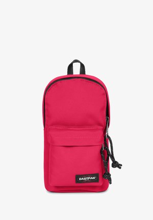 Zaino in nylon rosso con forma arrotondata, dotato di una tasca frontale, dettagli neri e un anello per appenderlo. Logo visibile sulla parte frontale.