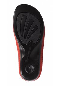 Child's red shoe sole with black rubber tread, textured grip, and brand logo visible on the heel area.