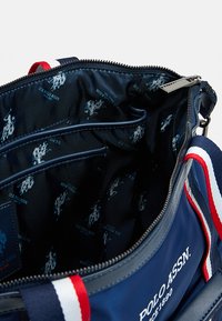 Borsa blu navy con chiusura a zip, fodera in tessuto con motivo logo ripetuto, molteplici tasche interne e tracolla a righe.