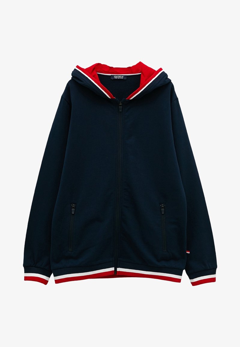 Sweat à capuche zippé bleu marine avec bordures à rayures rouges et blanches sur les poignets, l’ourlet et l’intérieur de la capuche, doté de poches latérales zippées.