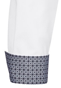 Weißes Hemd mit Ärmel, der einen kontrastierenden Bund mit einem blauen geometrischen Muster, glatter Textur und strukturiertem Schnitt aufweist.