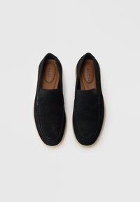 Sorte semskede slip-on sko med en glatt overdel, avrundet tå og lys gummisåle. Innvendig har de en tan fotseng med merke.