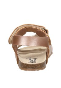 Braune Leder-Sandale mit offenem Zehenbereich, verstellbarem Knöchelriemen, konturiertem beigen Fußbett und Korksohle, von hinten betrachtet.