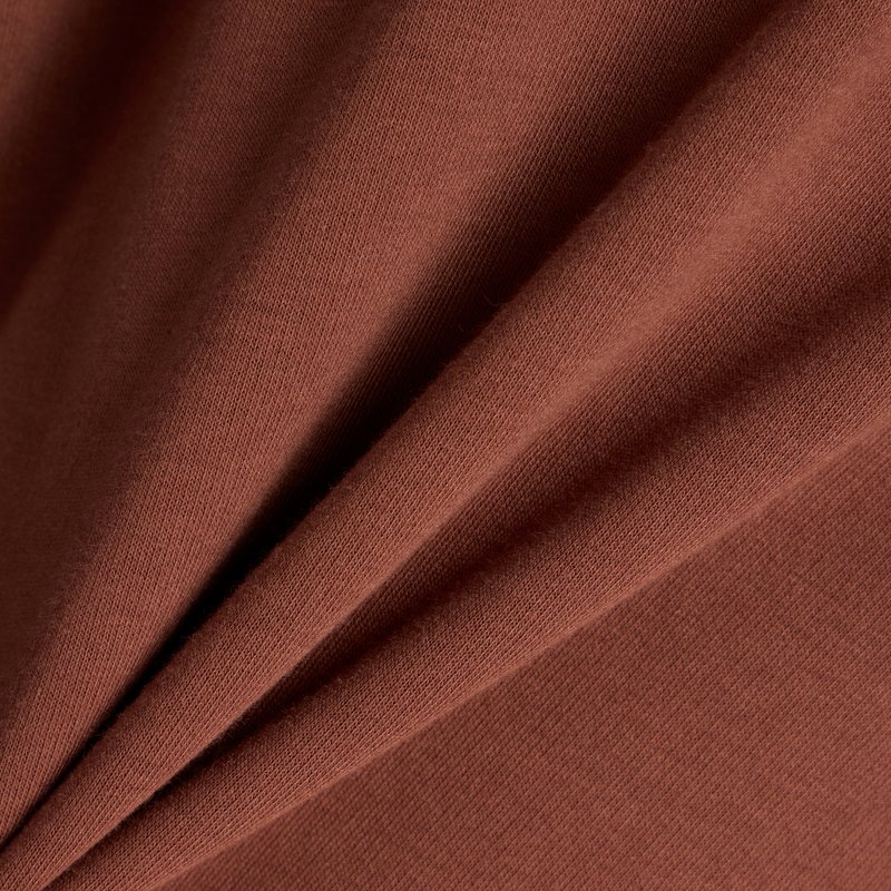 Brauner Baumwollstoff mit einer weichen Textur, gefaltet, um sein glattes, gleichmäßiges Gewebe und die reiche Farbe zur Geltung zu bringen. Keine Muster oder Hardware sichtbar.