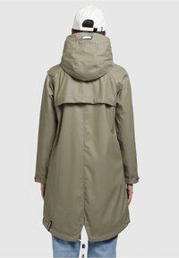 Oliven grøn vandtæt jakke med stor hætte, justerbar snøre og bagvedhold. Har standard jacket ærmer og en let forlænget snit.