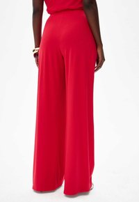 Wide-leg red trousers made of soft fabric; smooth texture with a fitted waistband. No visible patterns or hardware details.
