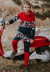 Czerwono-granatowy zestaw do noszenia w domu z kapturem, ozdobiony zabawnymi wzorami kostek do gry i grzybów; tkanina ma miękką fakturę, zestawiony z szarymi trampkami.