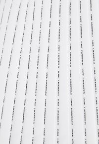 Cuaderno blanco con delgadas líneas de texto negro horizontales que presentan una marca repetida. Textura suave, tapa blanda y diseño minimalista.