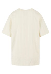 Camiseta de manga corta color crema con sutiles rayas verticales, corte relajado, escote redondeado y material de algodón suave.