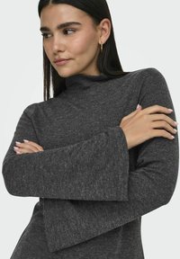 Mörkgrå, texturerad turtleneck-top med utsvängda ärmar. Designen har en snygg finish och en lös, avslappnad passform.