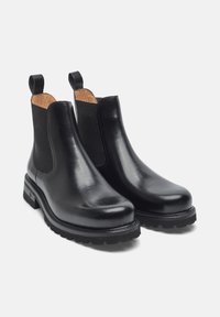 Stivali Chelsea in pelle nera con pannelli elastici laterali, linguette per il trascinamento e suola robusta con finitura testurizzata. Superficie liscia e design moderno.