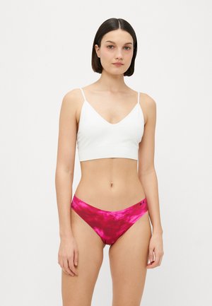 Fehér, rövidített bralette vékony pántokkal, amelyet rózsaszín, batikolt bikinialsóval párosítottak. Mindkettő sima, rugalmas anyagú.