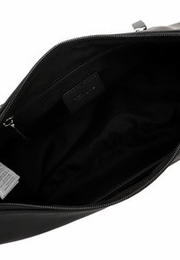 Black leather handbag interior with a smooth texture, a side zip pocket, and a fabric lining. Features a brand label and care tags.