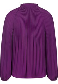 Liila pleatattu pusero pitkillä hihoilla, rypytetty pääntie ja elastiset hihansuut. Sujuva tekstuuri, virtaava muotoilu, rypytetty yksityiskohta selässä.