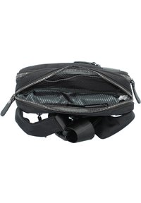 Černá látková crossbody taška s několika zipovými kapsami, texturovaným exteriérem, nastavitelným popruhem a podšívkou s geometrickým vzorem.