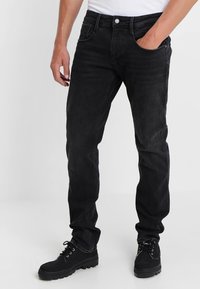 Svarta denimjeans med rak passform, femficksdesign och kontrasterande sömmar. Kombineras med svarta snörstövlar.