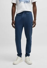 Navy blue sweatpants with elastic waistband and drawstring, tapered leg design, featuring contrasting stitching and a small logo.