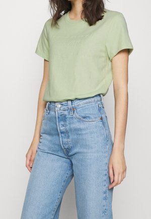 Jasnozielona bawełniana koszulka z krótkim rękawem, z wypukłym logo Levi's na piersi, zestawiona z jasnoniebieskimi dżinsami z wysokim stanem.