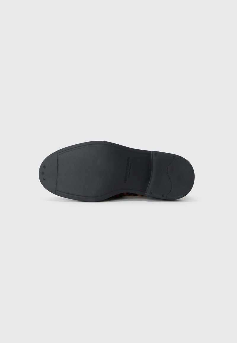 Suola di scarpa in gomma nera con una texture liscia, punta arrotondata e tacco leggero. Presenta un design pulito con dettagli minimi.