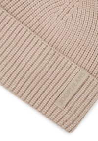 Close-up van beige geribbelde gebreide stof met een gevouwen rand en een beige label met de tekst "JOOP! JEANS."